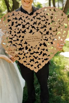 a man and woman holding up a heart shaped paper cutout with hearts on it