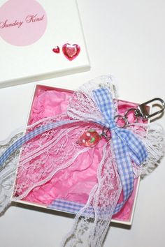 a pink and white box with lace on it next to a pair of heart shaped scissors