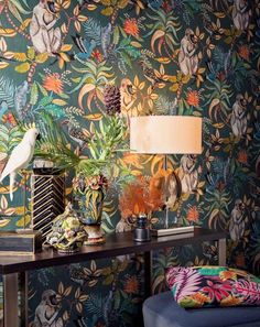 a living room with wallpaper that has birds and flowers on it, along with a blue ottoman