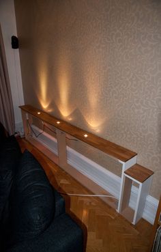 a living room with a couch and some lights on the wall next to a shelf