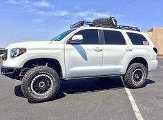 a white truck parked in a parking lot with luggage on the top of it's roof