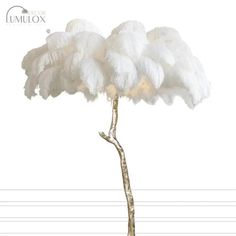 a tall white flower sitting on top of a wooden branch in front of a white wall