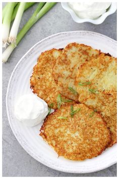 two crab cakes on a white plate with sour cream and celery next to it