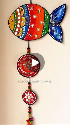 a colorful fish wind chime hanging from a wall