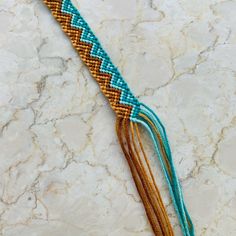 a close up of a tassel on a white marble counter with blue and brown beads