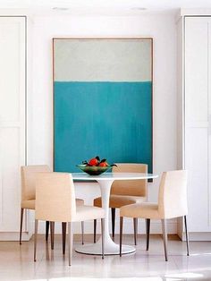 a dining room table with four chairs and a bowl of fruit on top of it