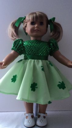 the doll is wearing a green dress with shamrocks on it's chest and white shoes