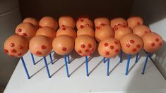 many brown eggs with red crosses on them are lined up on small blue sticks in front of a white counter