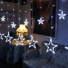 some white stars hanging from the ceiling in a room with a chair and lamp next to it