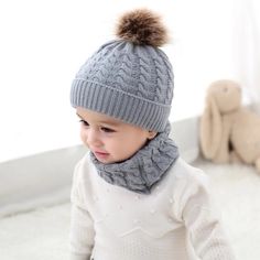 a small child wearing a hat and scarf with a pom - pom on top