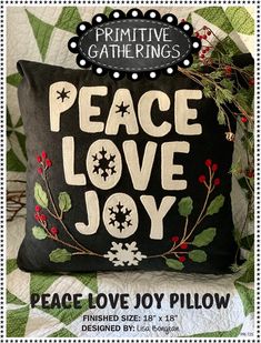 a pillow with the words peace love joy written on it and holly decorations around it