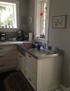 a kitchen with white cabinets and stainless steel counter tops, along with a rug on the floor