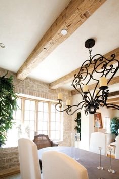 a chandelier hanging from the ceiling in a dining room with white chairs and table