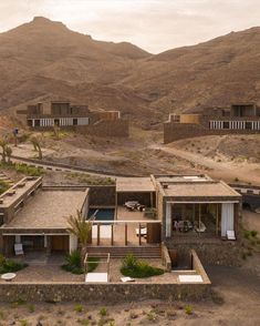 an aerial view of a house in the desert with mountains in the backgroud