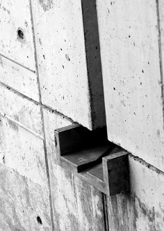 a black and white photo of a cement wall with a square opening in the middle