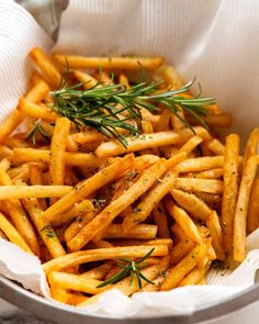 a bowl filled with french fries covered in seasoning and sprinkled with rosemary