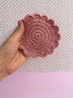 a hand holding a crocheted doily in front of a polka dot wall