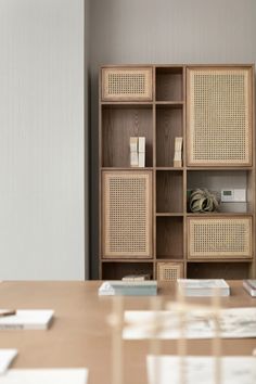 a wooden table sitting next to a book shelf with books on top of it in front of a white wall