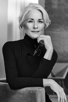 a black and white photo of a woman sitting in a chair with her hand on her chin