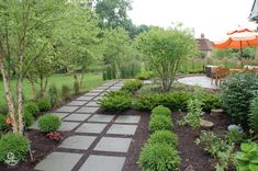 an outdoor patio area with stone walkways and plants in the foreground, surrounded by trees