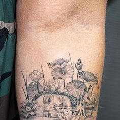 a tattoo on the arm of a man with flowers and water lilies in it