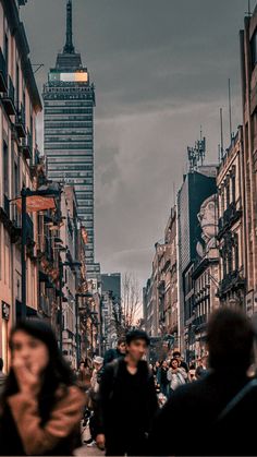 people walking down the street in front of tall buildings