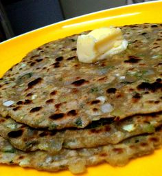 three flatbreads on a yellow plate topped with butter