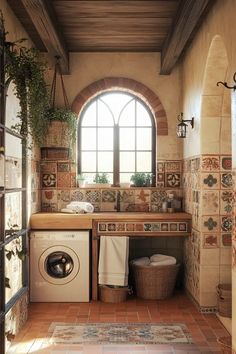 a washer and dryer in a bathroom with tile flooring, arched window, and tiled walls