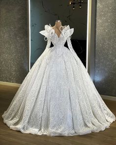 a white wedding dress on display in front of a wall with chandelier lights