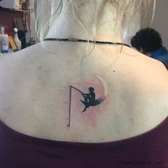 a woman with a tattoo on her back is looking at the moon and fishing pole