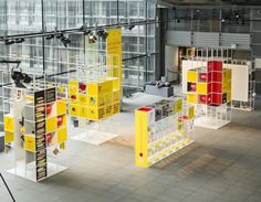 several yellow and red bookshelves in a large room with people walking around them