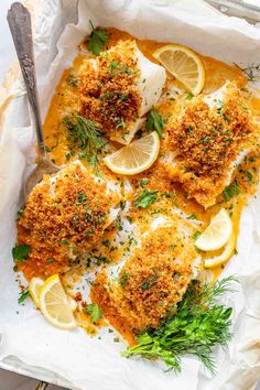 baked fish fillets with lemons and parsley in a baking dish on parchment paper