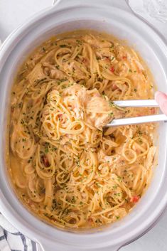 someone is holding two chopsticks in a bowl of noodles with sauce and parsley