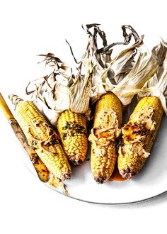 grilled corn on the cob with butter and brown sauce in a white plate