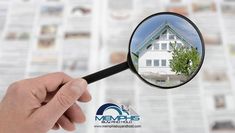 a hand holding a magnifying glass looking at a house in front of it