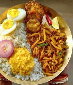 a plate with rice, eggs, and other foods on it is being held by someone's hand