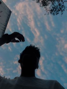 a man is looking up at the sky with his hand in front of him while holding a piece of paper