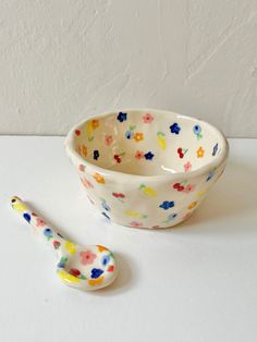 a bowl and spoon sitting next to each other on a white counter top with a wall in the background