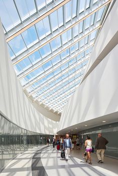 people are walking around in an open area with skylights on the ceiling and windows above them