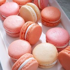 there are many pink and orange macaroons on the plate