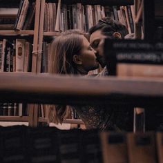 a man and woman kissing in front of a bookshelf