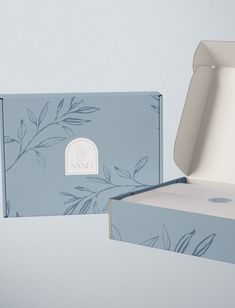 an open box with the lid opened and sitting next to another box that has a flower design on it