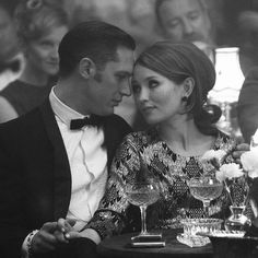 a man and woman sitting at a table with wine glasses