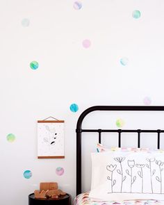 a bed room with a neatly made bed and polka dot wall decals