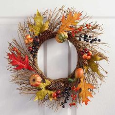 a wreath with autumn leaves and berries hanging on the front door, ready to be decorated