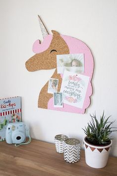 a pink unicorn head mounted to the side of a wall next to a potted plant