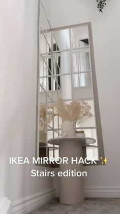 a mirror that is on the side of a wall next to a vase with flowers in it