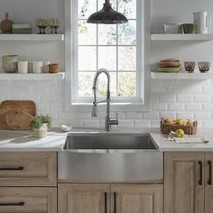 a kitchen with wooden cabinets and stainless steel sink, open shelves on the wall above