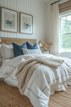 a bed with white linens and blue pillows in a bedroom next to a window