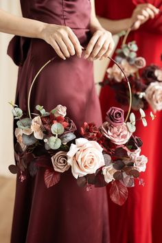 two bridesmaids in red dresses hold their bouquets with roses and eucalyptus leaves